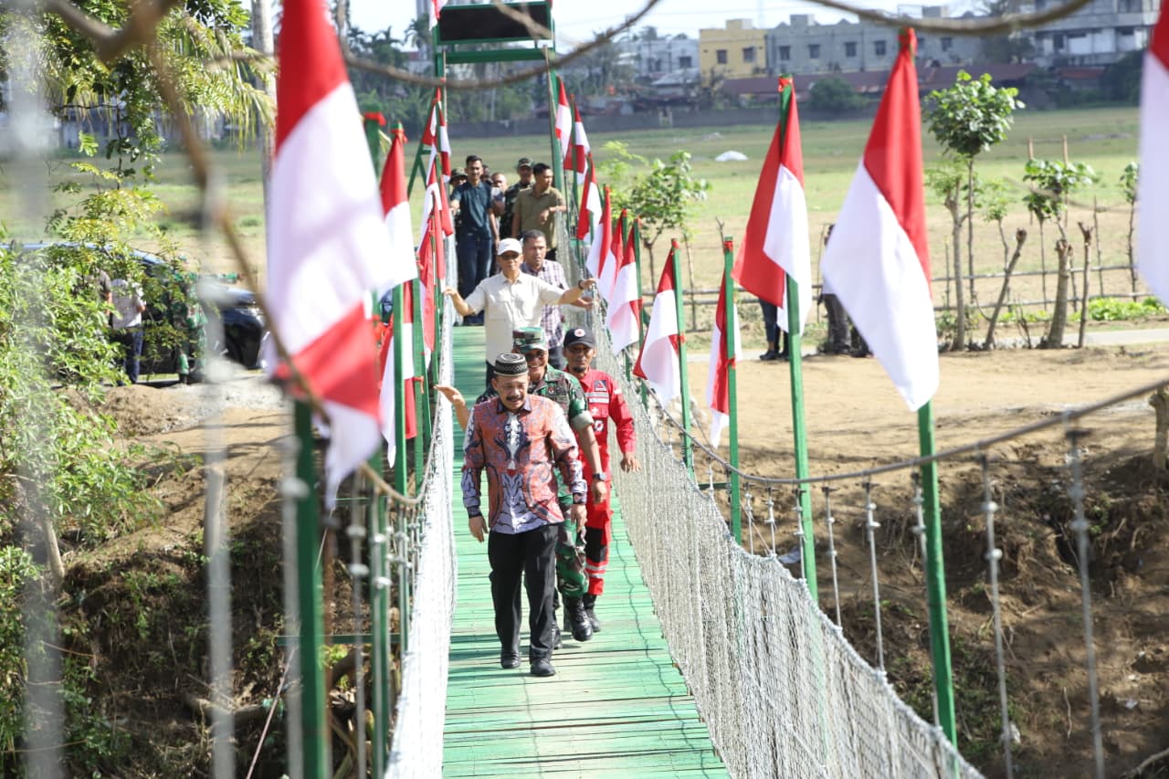 Bupati Pidie Sarjani Abdullah, meninjau jembatan gantung yang menghubungi Kecamatan Mutiara dan Mutiara Timur, Minggu (7/2/2026). (Foto.IST).
